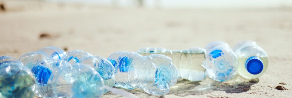 Plastic bottles scattered on the sand of a sunny beach.