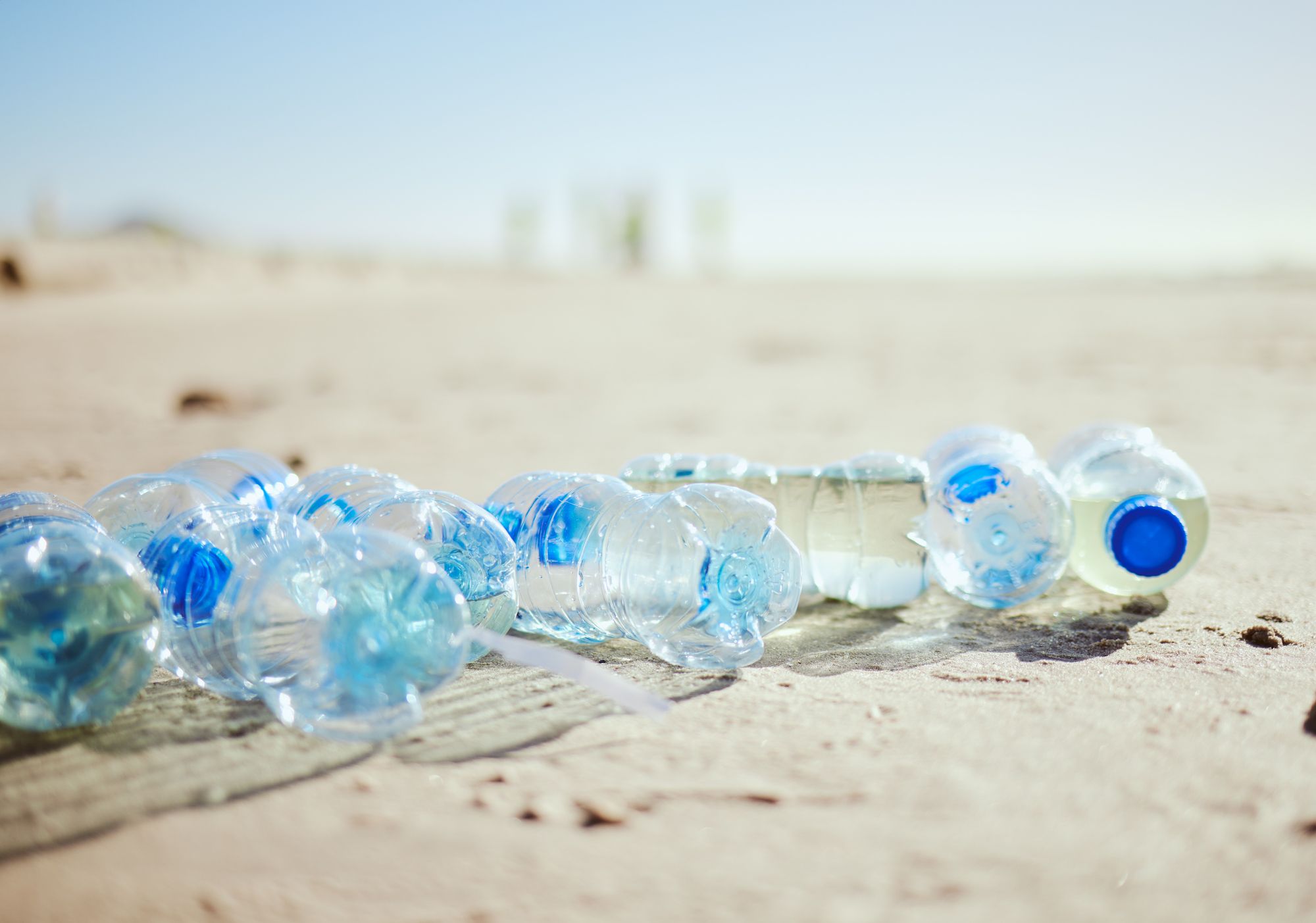 Plastic bottles scattered on the sand of a sunny beach.