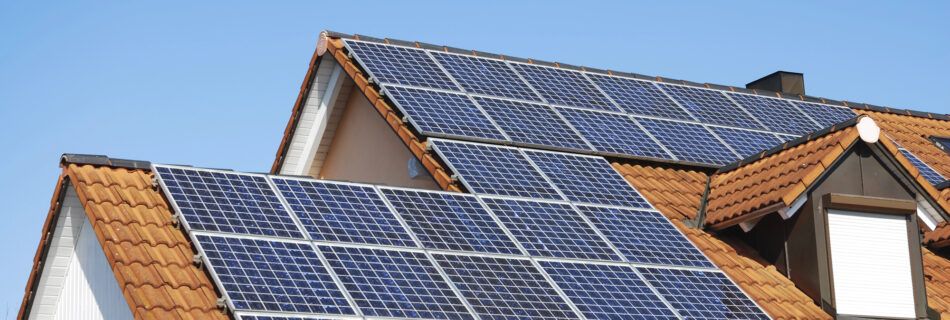 A house roof with solar panels under a clear blue sky.